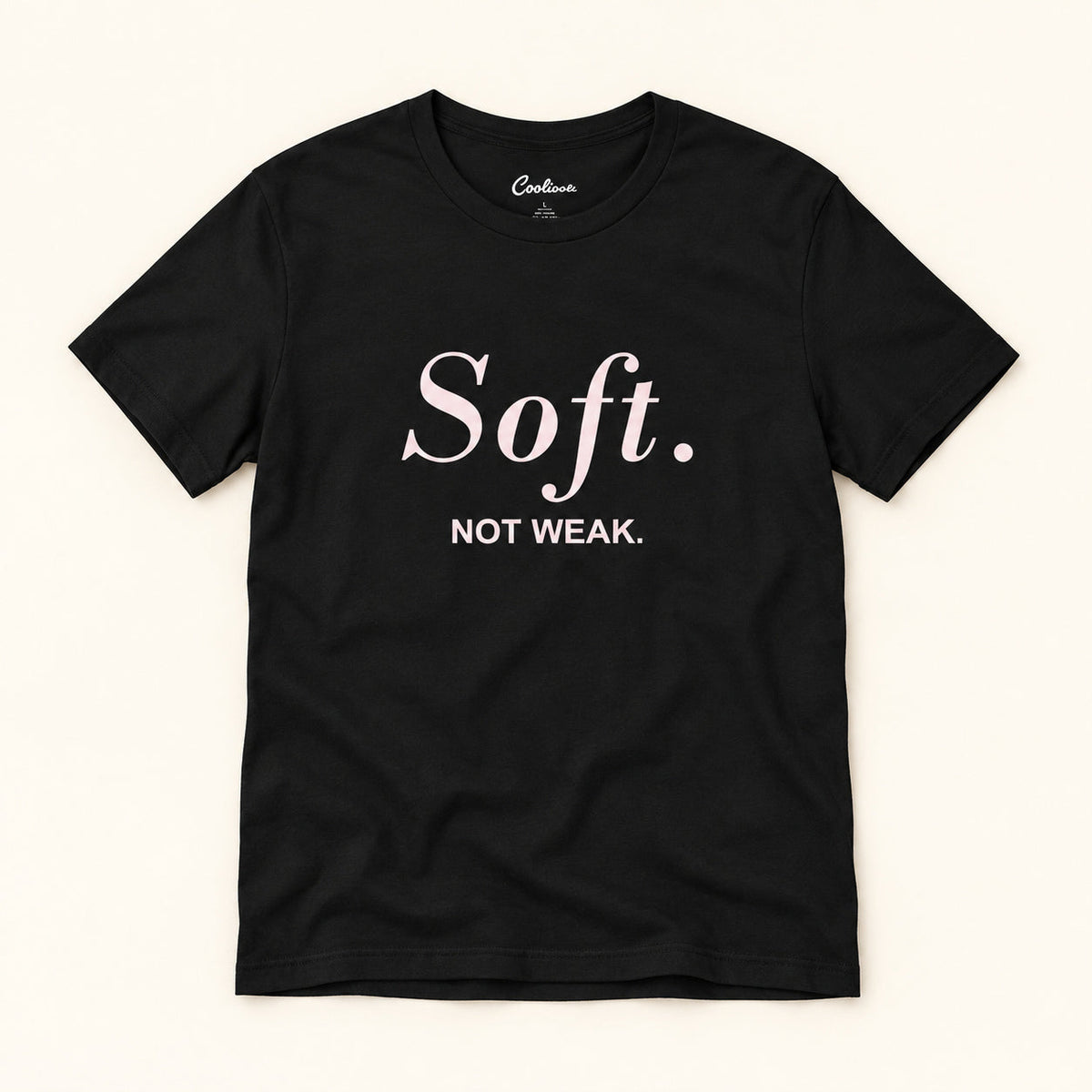 Soft. Not Weak. affirmation tee in Black on a warm neutral studio background