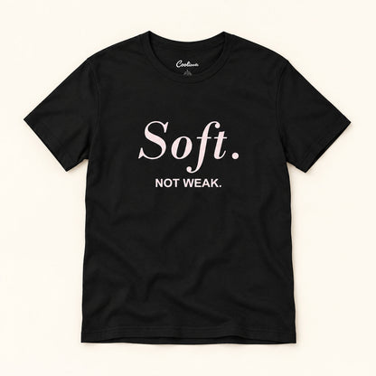 Soft. Not Weak. affirmation tee in Black on a warm neutral studio background