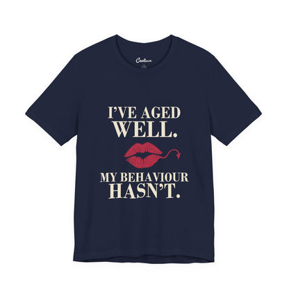 Navy Cooliooli Bella+Canvas 3001 T-shirt with “I’ve aged well. My behaviour hasn’t.” lettering and lipstick kiss with devil tail, front flat lay