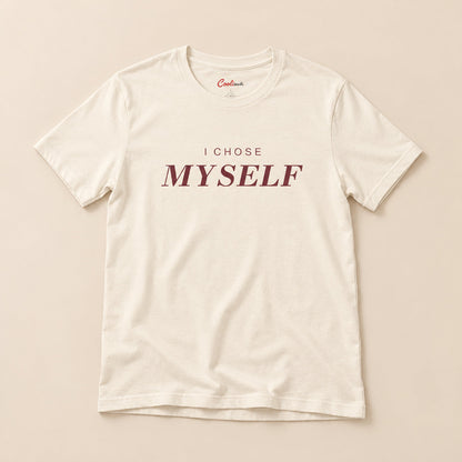 Her First Choice. Natural Bella+Canvas 3001 T-shirt with I CHOSE MYSELF lettering, complete overhead flat lay on a warm neutral background.