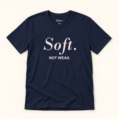 Soft. Not Weak. affirmation tee in Navy on a warm neutral studio background