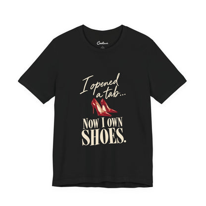 Black Cooliooli T-shirt with red heels and “I opened a tab… Now I own shoes.” lettering, front flat lay