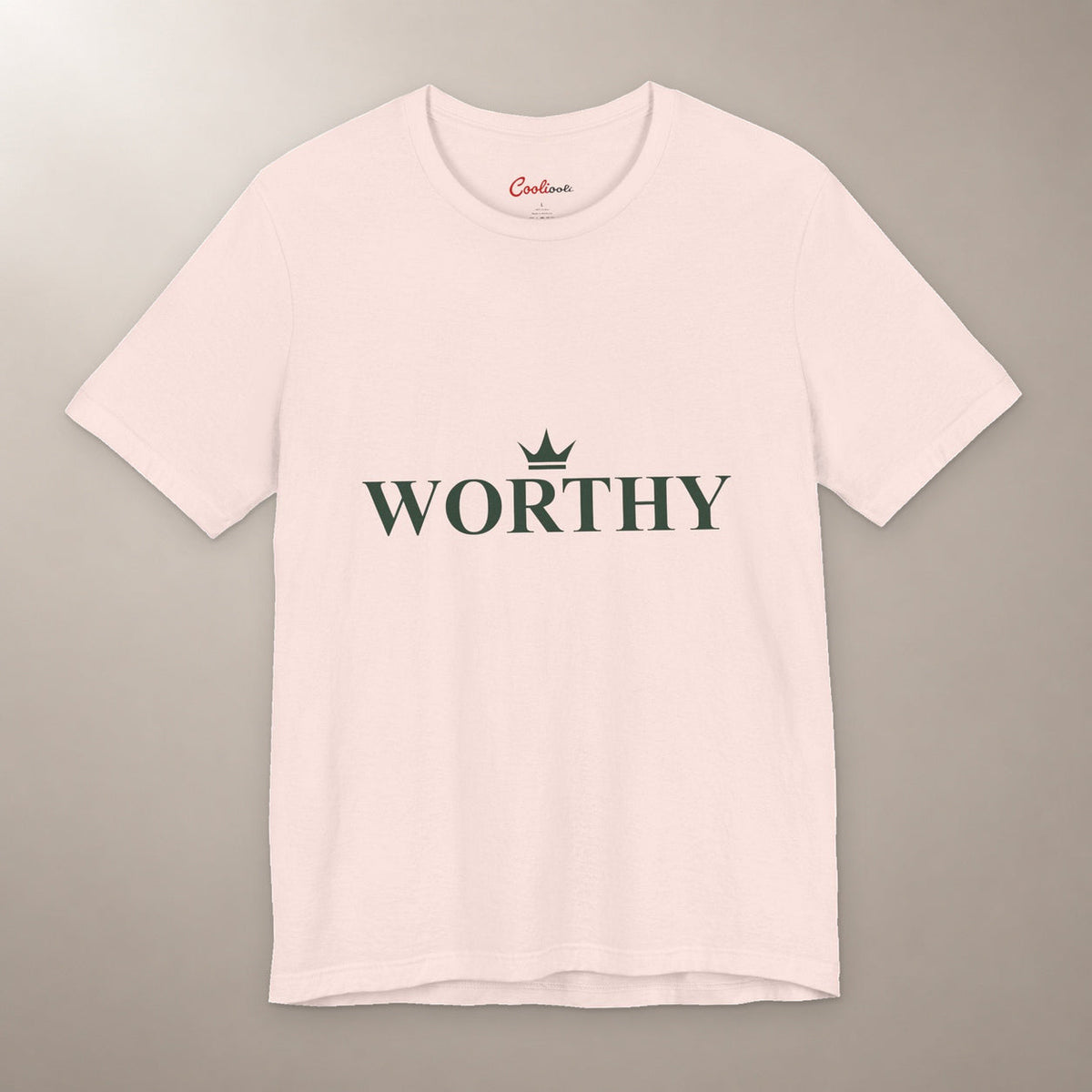 Her Worth Was Never in Question. Bella+Canvas 3001 T-shirt in Soft Pink, front flat lay with Worthy lettering and a small crown on a plain warm neutral background.