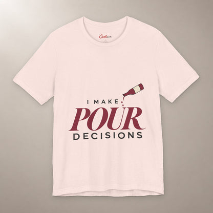 Blame the Vintage. Bella+Canvas 3001 T-shirt in Soft Pink, front flat lay with I Make Pour Decisions lettering and a tilted wine bottle on a plain warm neutral background.