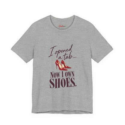 Athletic Heather Cooliooli T-shirt with red heels and “I opened a tab… Now I own shoes.” lettering, front flat lay