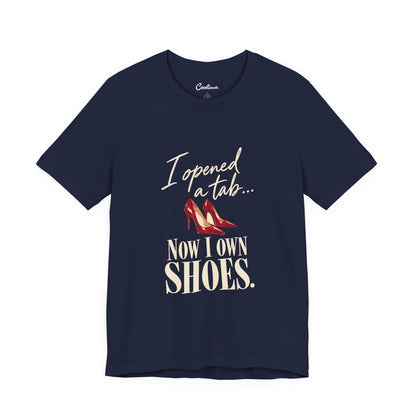 Navy Cooliooli T-shirt with red heels and “I opened a tab… Now I own shoes.” lettering, front flat lay