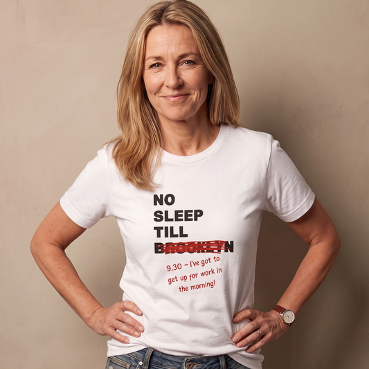 Woman in her fifties wearing a white No Sleep Till Brooklyn slogan t-shirt with a denim skirt, standing with hands on hips