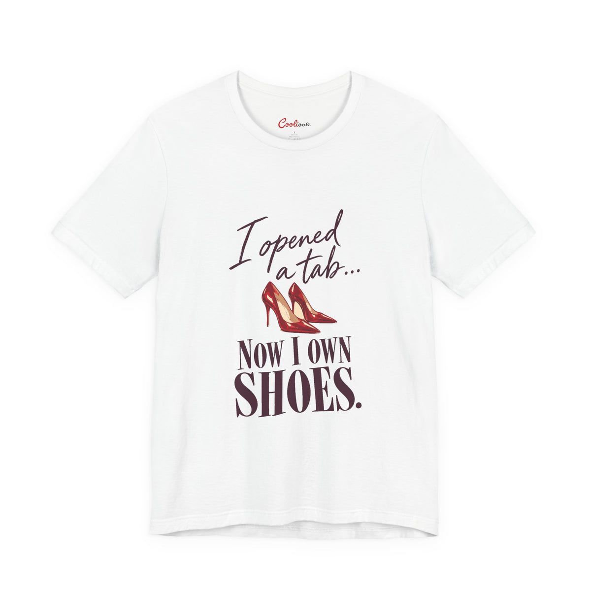 White Cooliooli T-shirt with red heels and “I opened a tab… Now I own shoes.” lettering, front flat lay