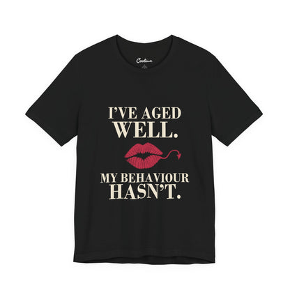 Black Cooliooli Bella+Canvas 3001 T-shirt with “I’ve aged well. My behaviour hasn’t.” lettering and lipstick kiss with devil tail, front flat lay