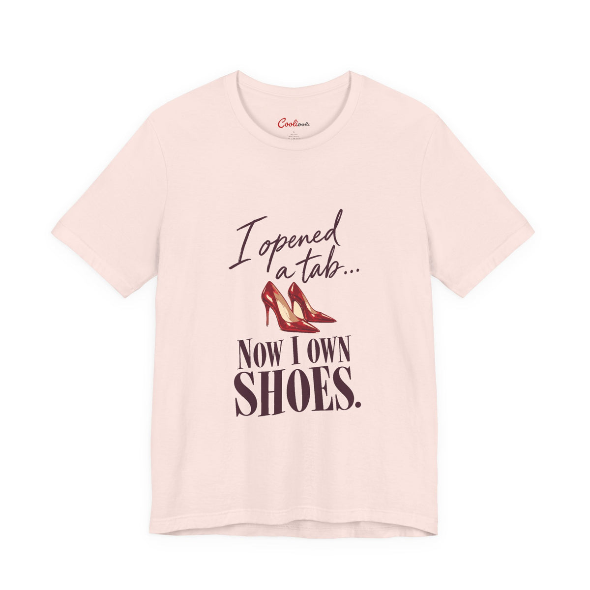 Soft Pink Cooliooli T-shirt with red heels and “I opened a tab… Now I own shoes.” lettering, front flat lay