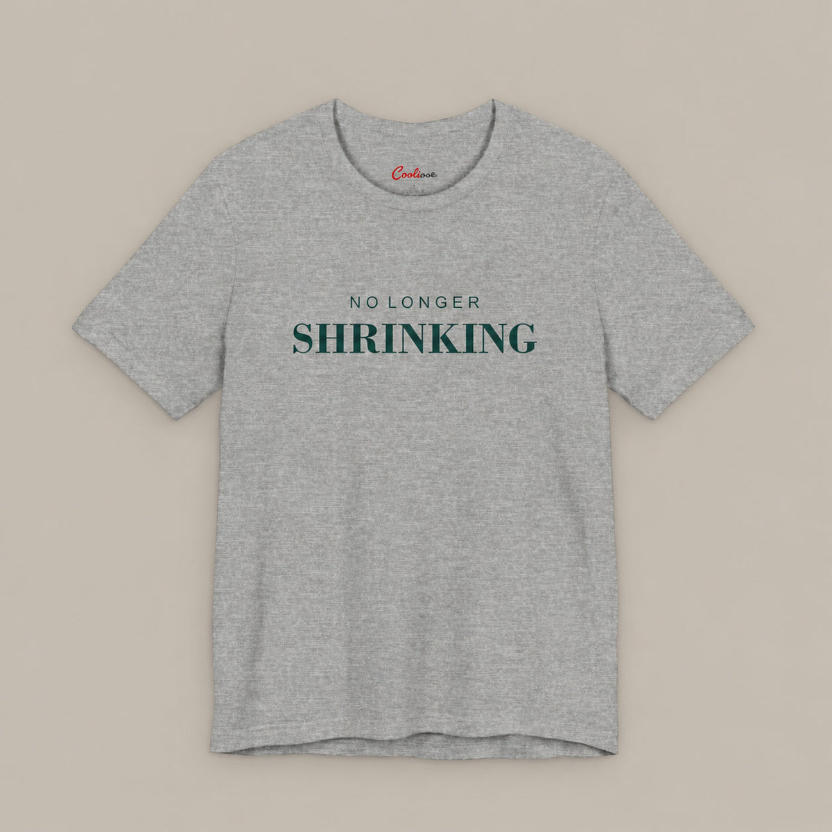 Athletic Heather NO LONGER SHRINKING Bella+Canvas 3001 tee with deep green lettering, complete square flat lay on a plain warm neutral background.