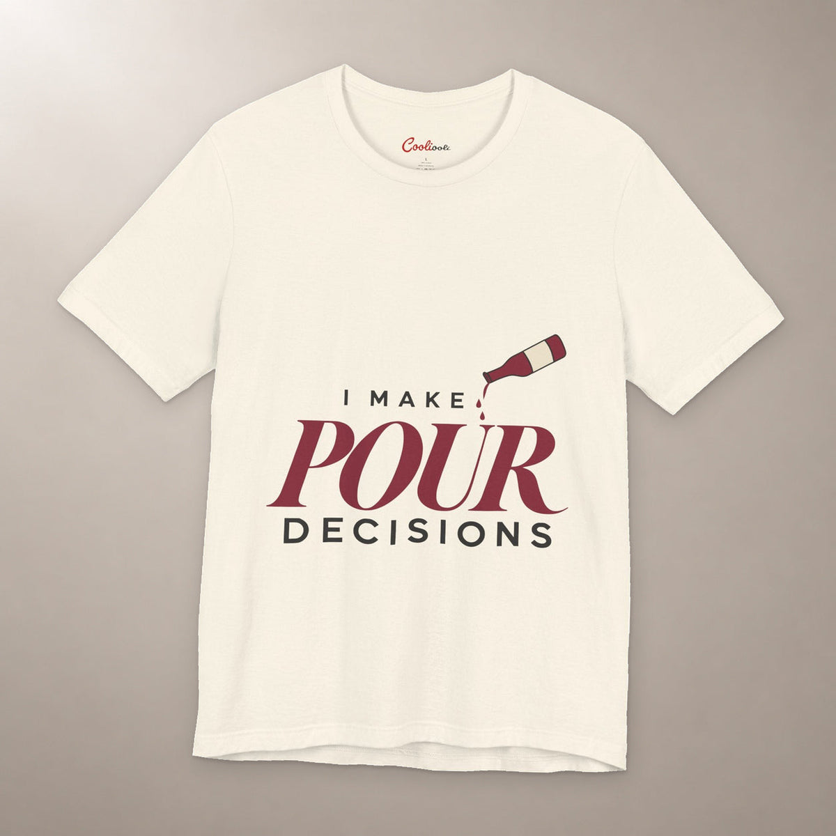 Blame the Vintage. Bella+Canvas 3001 T-shirt in Natural, front flat lay with I Make Pour Decisions lettering and a tilted wine bottle on a plain warm neutral background.