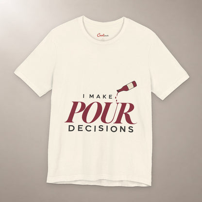 Blame the Vintage. Bella+Canvas 3001 T-shirt in Natural, front flat lay with I Make Pour Decisions lettering and a tilted wine bottle on a plain warm neutral background.