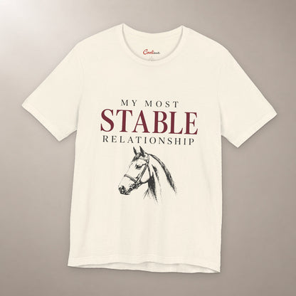 Finally, Someone Dependable. Bella+Canvas 3001 tee in natural, flat lay with My Most Stable Relationship lettering and a bridled horse on a plain warm neutral background.