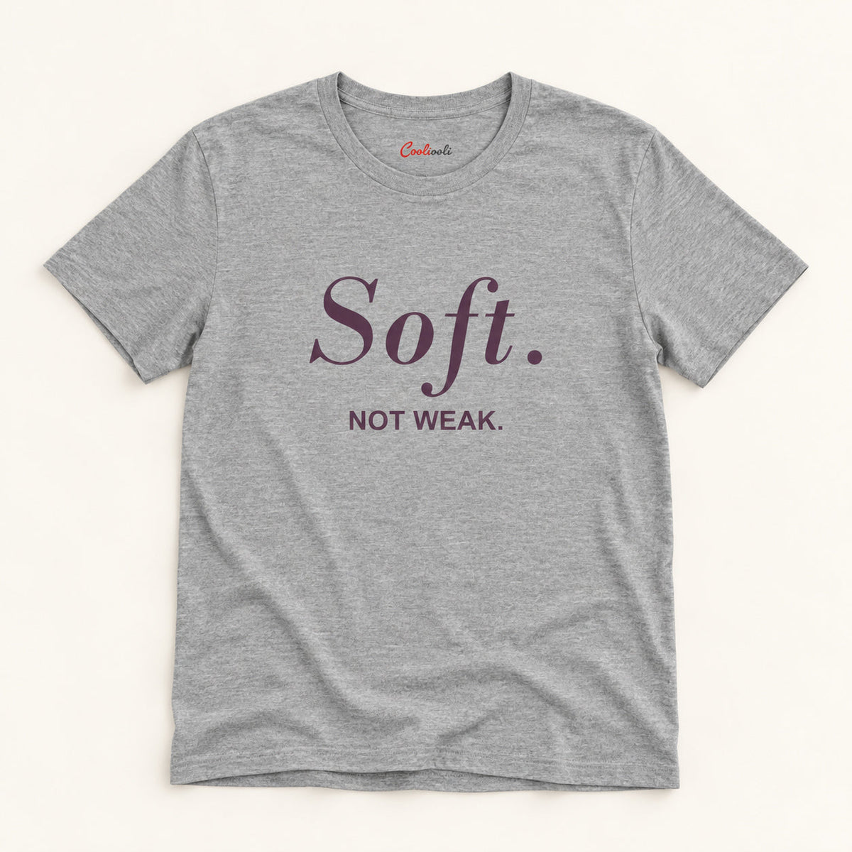 Soft. Not Weak. affirmation tee in Athletic Heather on a warm neutral studio background