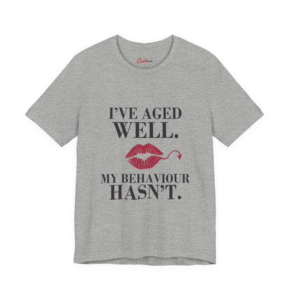 Athletic Heather Cooliooli Bella+Canvas 3001 T-shirt with “I’ve aged well. My behaviour hasn’t.” lettering and lipstick kiss with devil tail, front flat lay