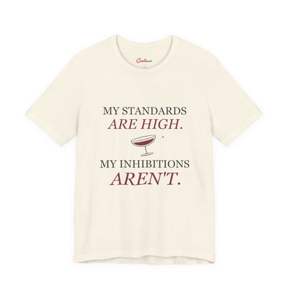 Natural Cooliooli Bella+Canvas 3001 tee with My standards are high. My inhibitions aren't. lettering and tipped cocktail coupe graphic, front flat lay.