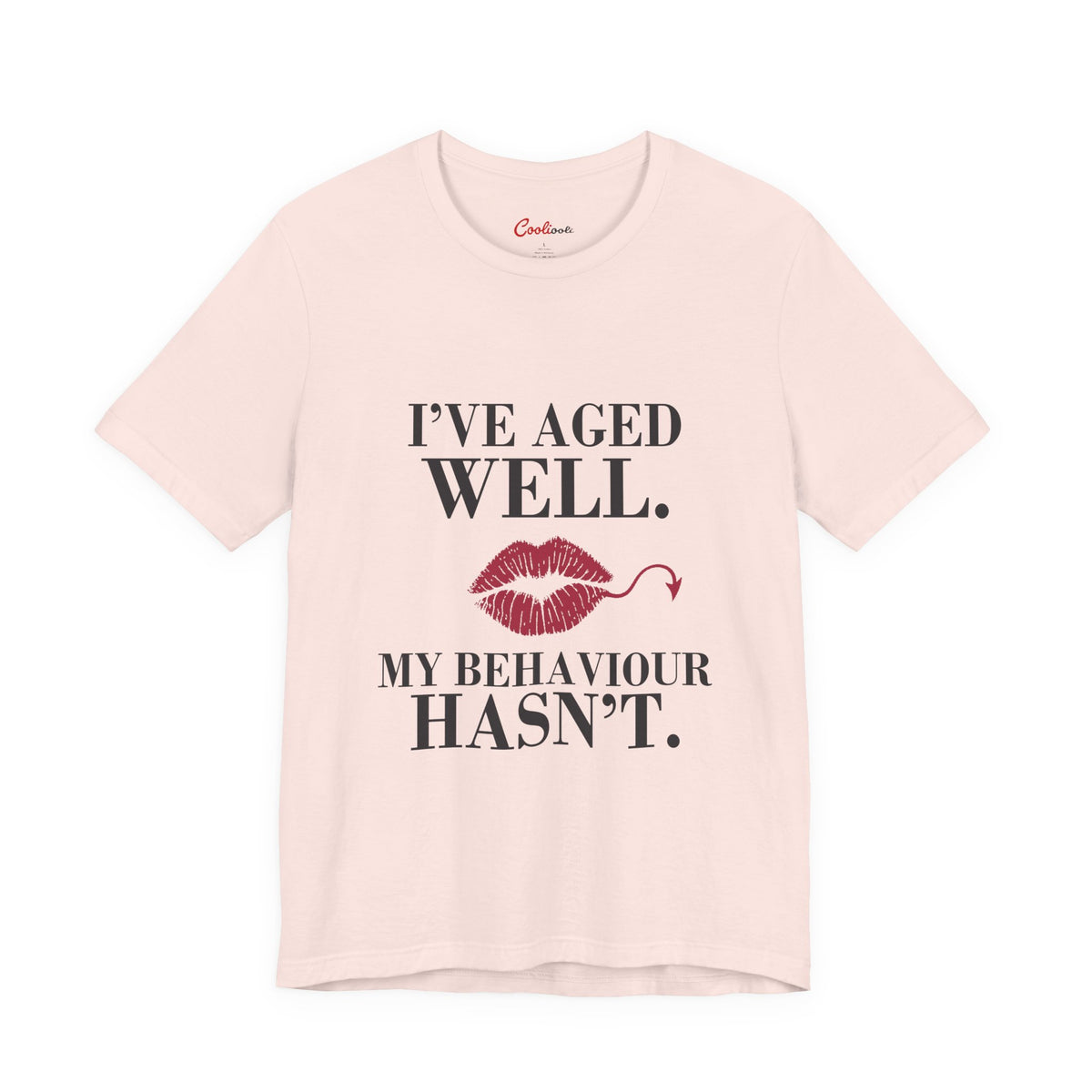 Soft Pink Cooliooli Bella+Canvas 3001 T-shirt with “I’ve aged well. My behaviour hasn’t.” lettering and lipstick kiss with devil tail, front flat lay