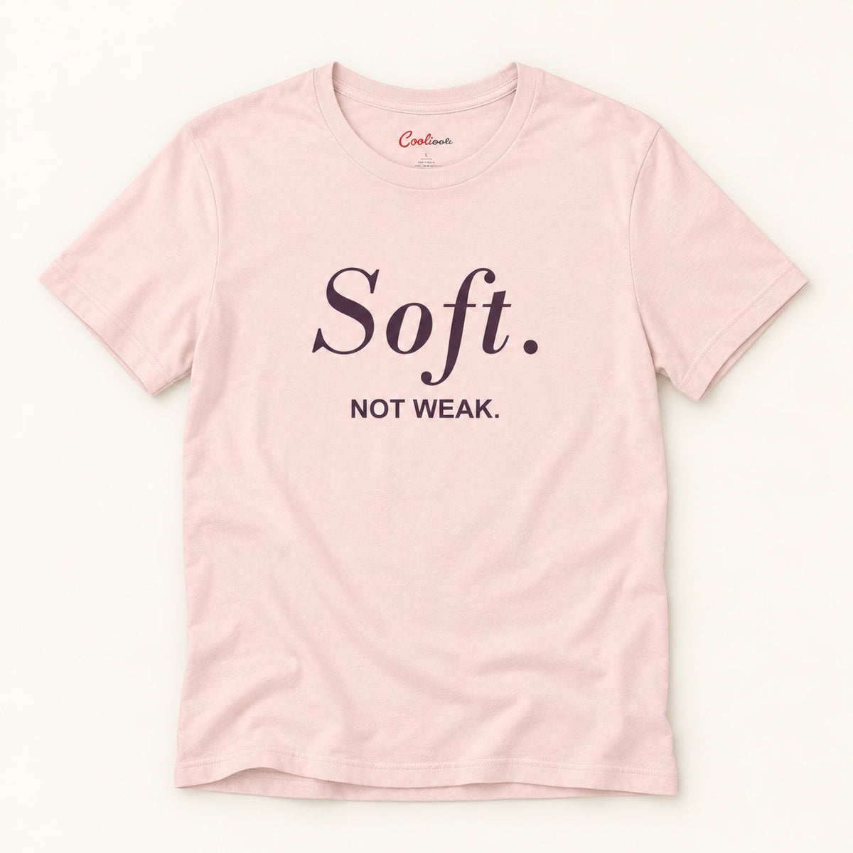 Soft. Not Weak. affirmation tee in Soft Pink on a warm neutral studio background
