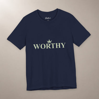 Her Worth Was Never in Question. Bella+Canvas 3001 T-shirt in Navy, front flat lay with Worthy lettering and a small crown on a plain warm neutral background.