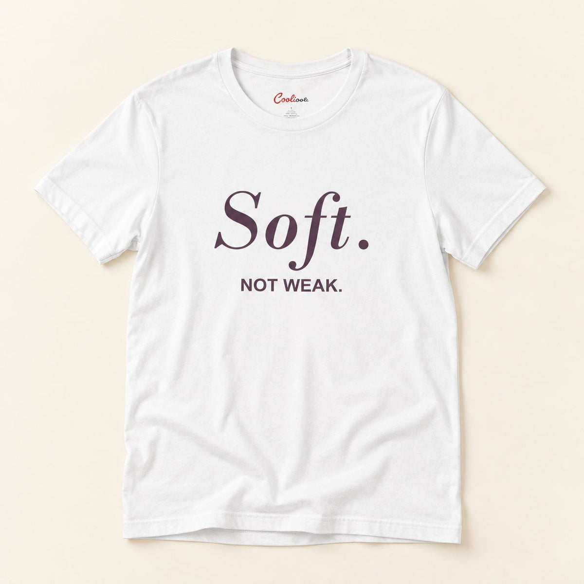 Soft. Not Weak. affirmation tee in White on a warm neutral studio background