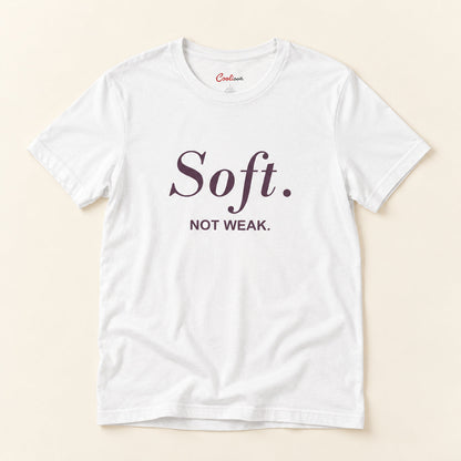 Soft. Not Weak. affirmation tee in White on a warm neutral studio background