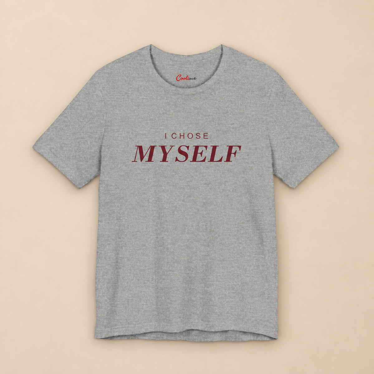 Her First Choice. Athletic Heather Bella+Canvas 3001 T-shirt with burgundy I CHOSE MYSELF lettering and Cooliooli neck print, complete square flat lay on a warm neutral background.