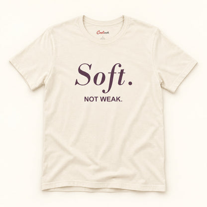 Soft. Not Weak. affirmation tee in Natural on a warm neutral studio background