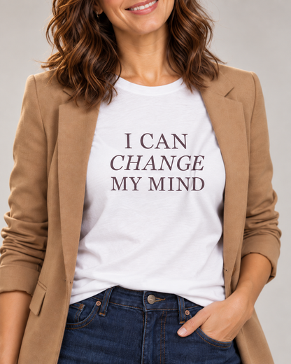 Collar-to-hip detail of the White I Can Change My Mind T-shirt with plum serif lettering and italic Change, worn beneath an open camel blazer.