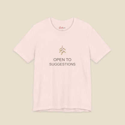 Soft Pink Bella+Canvas3001 Christmas T-shirt with a small bronze and cream mistletoe graphic and Open to Suggestions lettering.