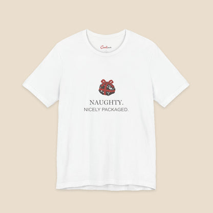 White Bella+Canvas 3001 Christmas T-shirt with an original coal and red bow illustration above Naughty. Nicely Packaged. lettering.