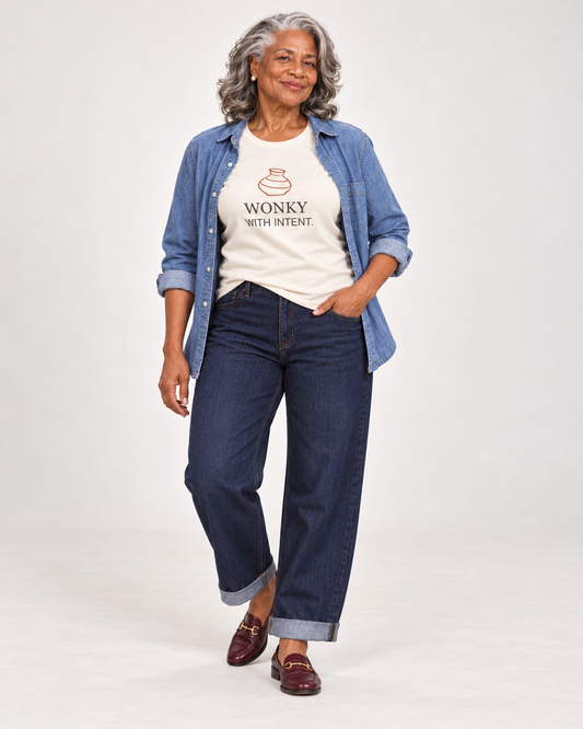 Vivienne wearing the Natural Wonky With Intent pottery T-shirt with an open blue overshirt, cuffed dark barrel jeans and burgundy loafers.