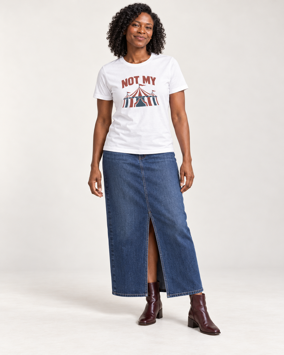 Amara wearing the White NOT MY circus tent Bella+Canvas3001 unisex tee with a denim maxi skirt and oxblood ankle boots in a pale studio.