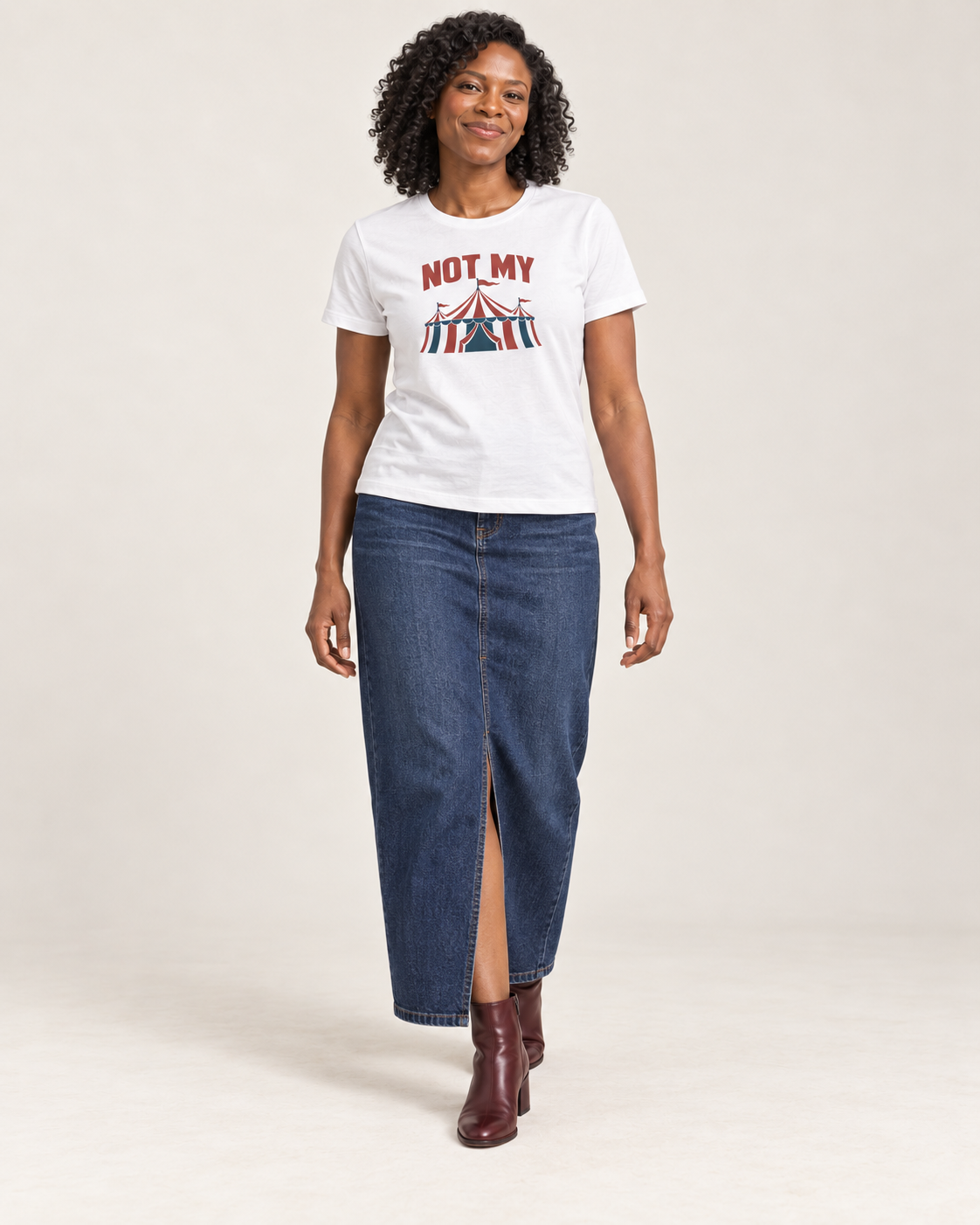 Amara wearing the White NOT MY circus tent Bella+Canvas6400 women’s relaxed-fit tee with a denim maxi skirt and oxblood ankle boots in a pale studio.