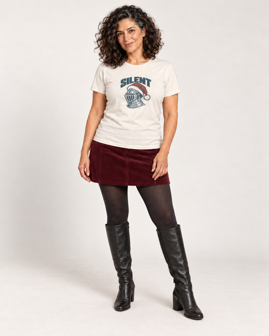 Leila wearing the Natural SILENT silver knight and Santa hat Bella+Canvas 3001 unisex tee with a burgundy corduroy mini skirt, tights and black tall boots in a pale studio.