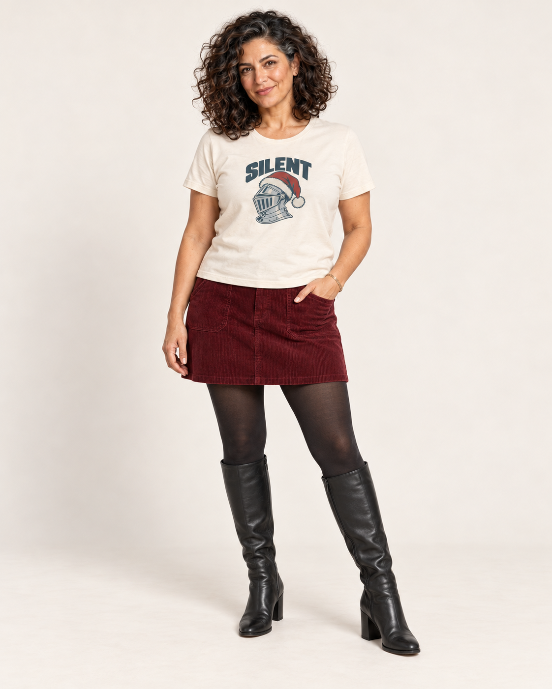 Leila wearing the Natural SILENT silver knight and red Santa hat Bella+Canvas 6400 women’s relaxed-fit tee with a burgundy corduroy mini skirt, tights and black tall boots.
