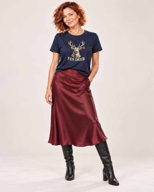 Sienna wearing the plain Navy YES DEER stag and one red bauble Bella+Canvas 6400 women’s relaxed-fit tee with burgundy satin midi skirt and black knee-high boots.
