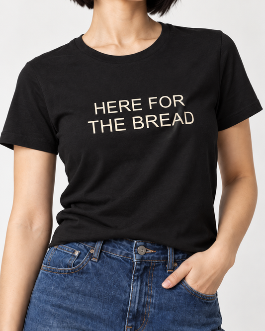 Close-up of cream Here for the Bread lettering on the black crewneck T-shirt.