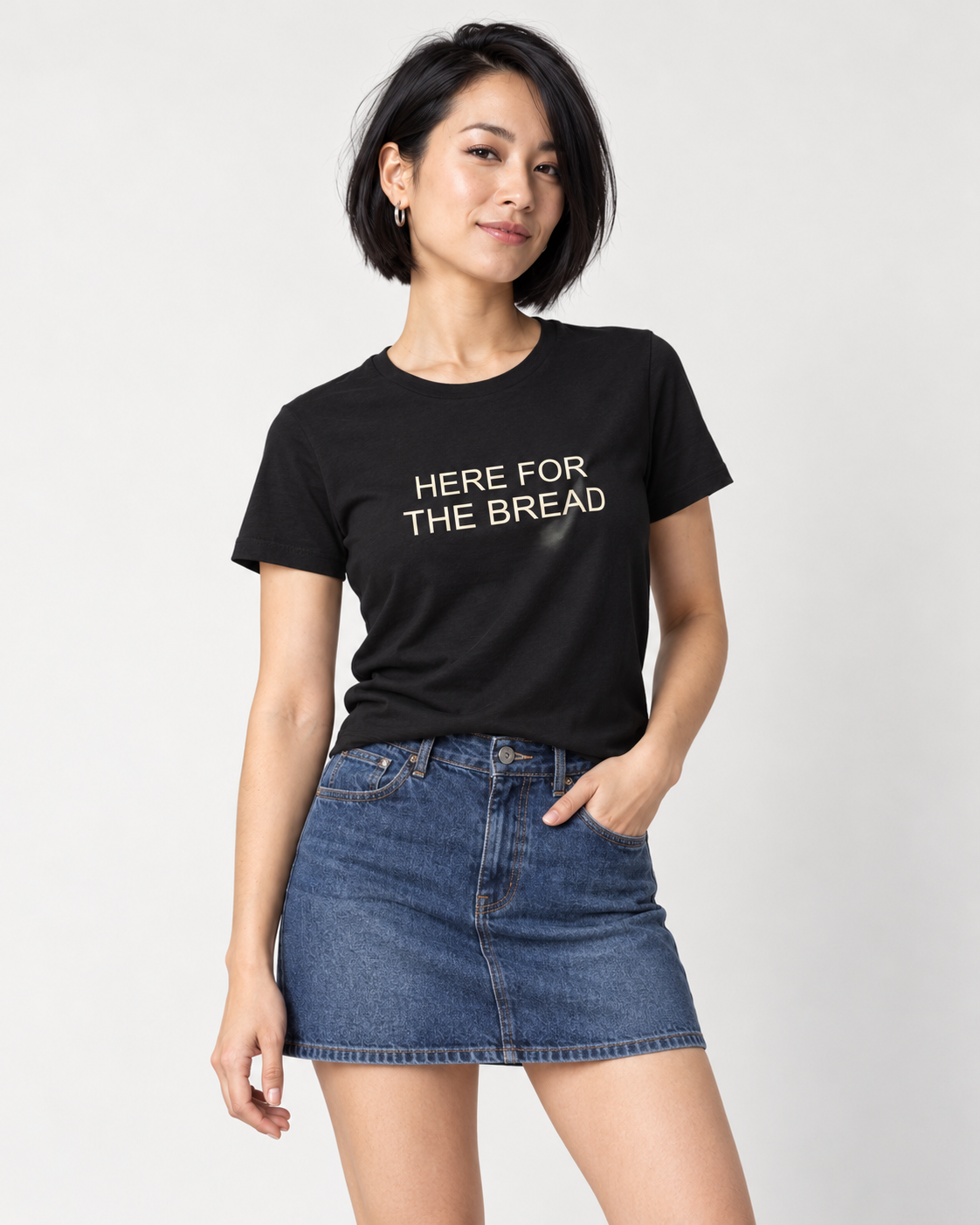 Mina wearing a black Here for the Bread Bella+Canvas3001 T-shirt with a denim mini skirt.