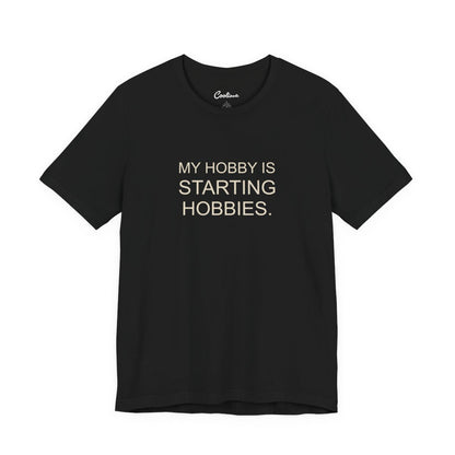 My Hobby Is Starting Hobbies Bella+Canvas3001 T-shirt in Black, full front supplier flat lay.