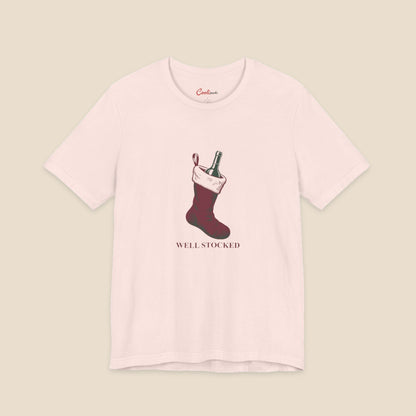Soft Pink Bella+Canvas3001 Well Stocked Christmas T-shirt with an original solid red wine-filled stocking illustration and serif lettering.