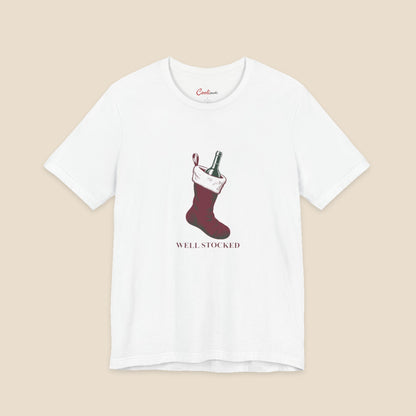 White Bella+Canvas3001 Well Stocked Christmas T-shirt with an original solid red wine-filled stocking illustration and serif lettering.