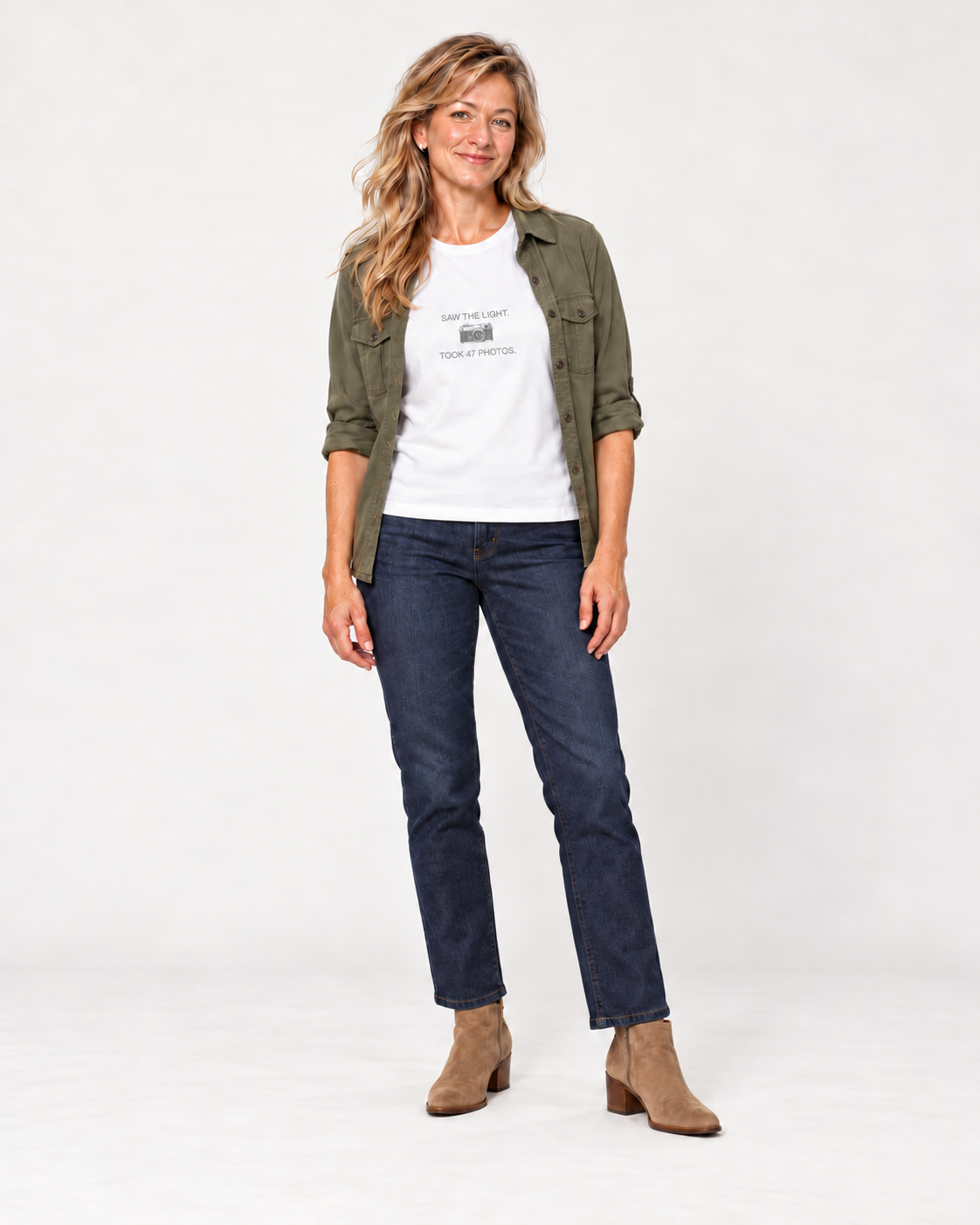 Elena wearing the White Saw the Light Took 47 Photos Bella+Canvas6400 women’s relaxed-fit tee with an open olive overshirt, indigo jeans and tan suede ankle boots.