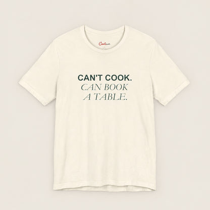 Can't Cook, Can Book a Table Bella+Canvas 3001 T-shirt in Natural, front flat lay.