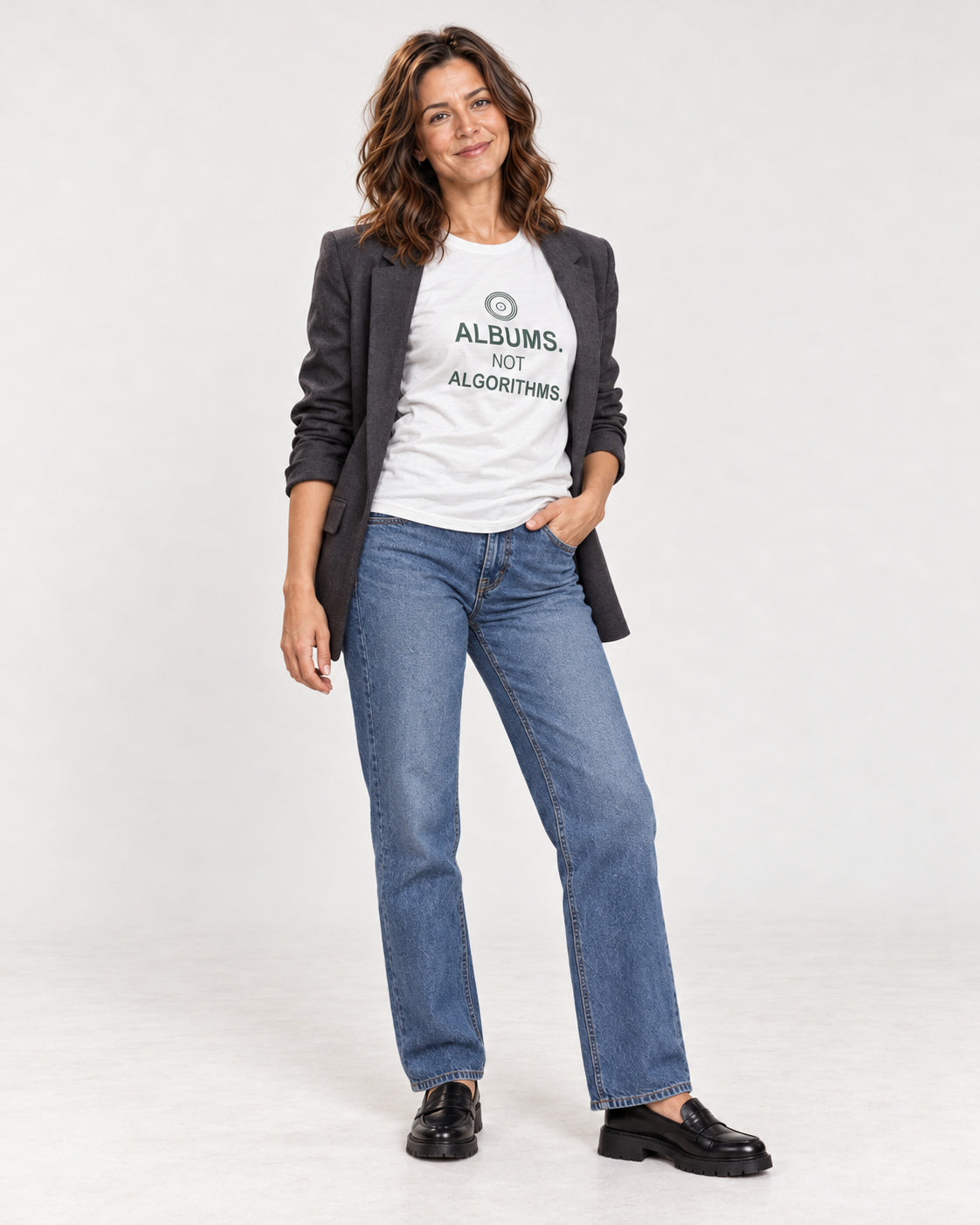 Sophie wearing the White ALBUMS. NOT ALGORITHMS. Bella+Canvas 3001 tee with an open blazer, jeans and loafers.