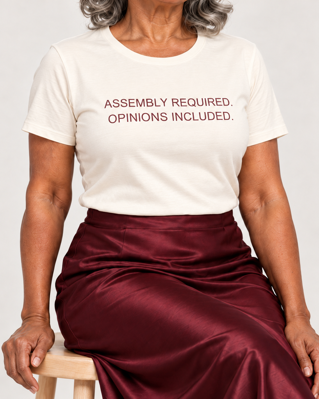 Close-up of the muted burgundy Assembly Required. Opinions Included. lettering on the Natural cotton crewneck T-shirt.