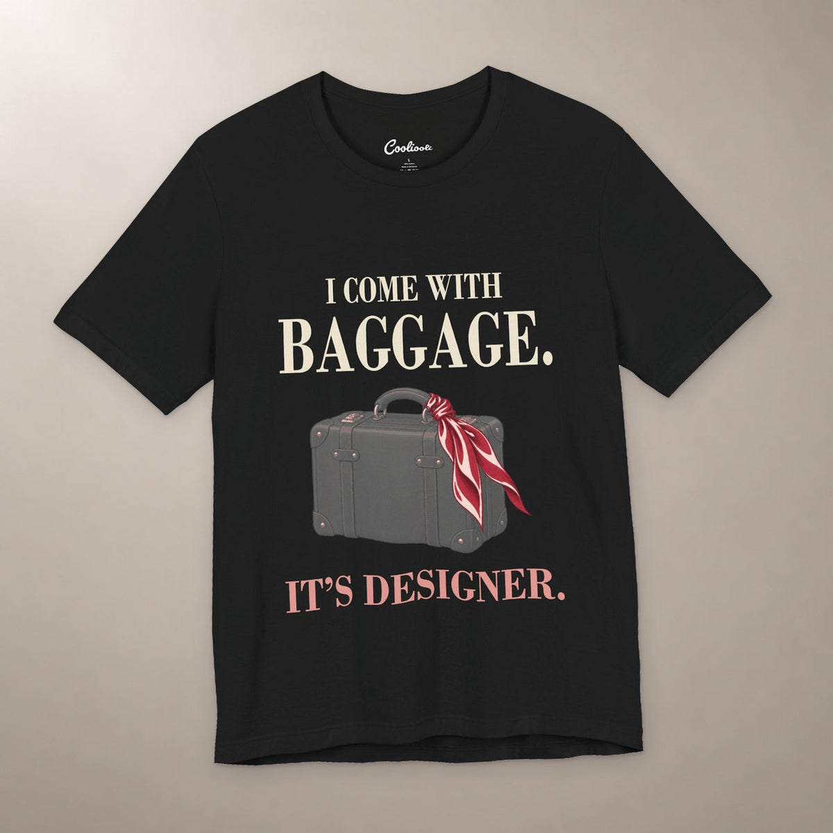 Excess Baggage. Excellent Taste. Bella+Canvas 3001 T-shirt in Black, front flat lay with I come with baggage. It’s designer. lettering and a vintage suitcase with a burgundy scarf on a plain warm neutral background.