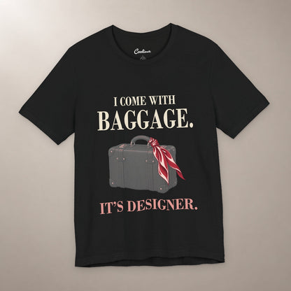 Excess Baggage. Excellent Taste. Bella+Canvas 3001 T-shirt in Black, front flat lay with I come with baggage. It’s designer. lettering and a vintage suitcase with a burgundy scarf on a plain warm neutral background.