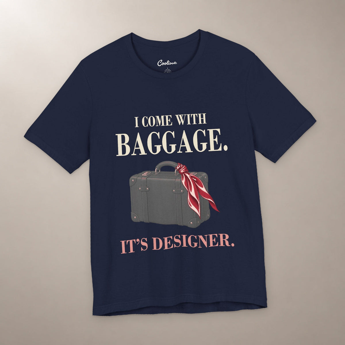 Excess Baggage. Excellent Taste. Bella+Canvas 3001 T-shirt in Navy, front flat lay with I come with baggage. It’s designer. lettering and a vintage suitcase with a burgundy scarf on a plain warm neutral background.