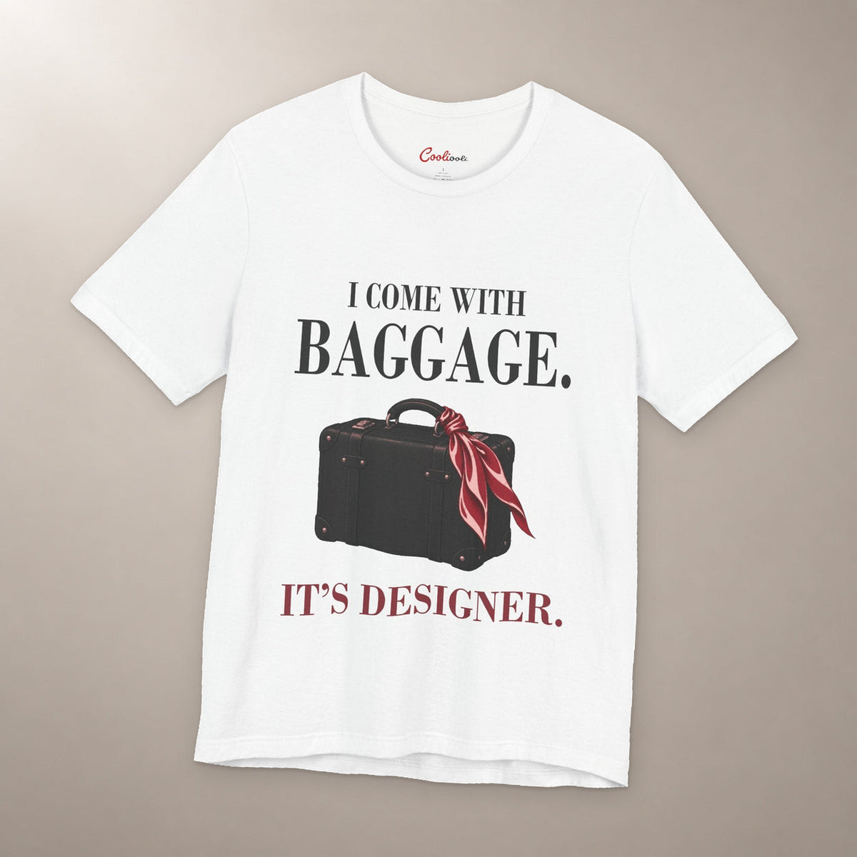 Excess Baggage. Excellent Taste. Bella+Canvas 3001 T-shirt in White, front flat lay with I come with baggage. It’s designer. lettering and a vintage suitcase with a burgundy scarf on a plain warm neutral background.